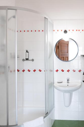 a white bathroom with a shower and a sink at Mleczarnia Hotel Restauracja in Chludowo