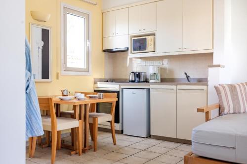 a kitchen with a table and a small kitchen with white cabinets at Louis Althea Beach in Protaras
