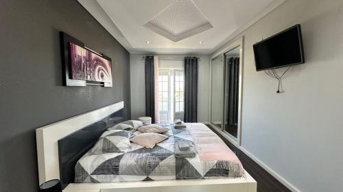 a bedroom with a bed and a flat screen tv at RIVABeach House in Lourinhã
