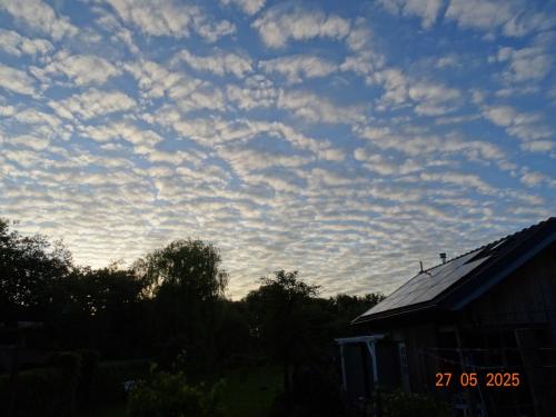 a cloudy sky above a house with a roof at Vakantieverblijf de Barre Hichte, Grindweg 4 Nijeberkoop in Nijeberkoop