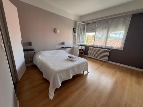 a bedroom with a white bed and a wooden floor at Hôtel La Pergola - centre ville in Capbreton
