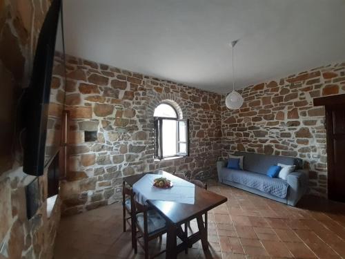 a living room with a table and a brick wall at Agriturismo Cuile Querce in Campanedda