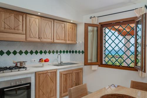 a kitchen with wooden cabinets and a glass window at Campos Varios in Orosei