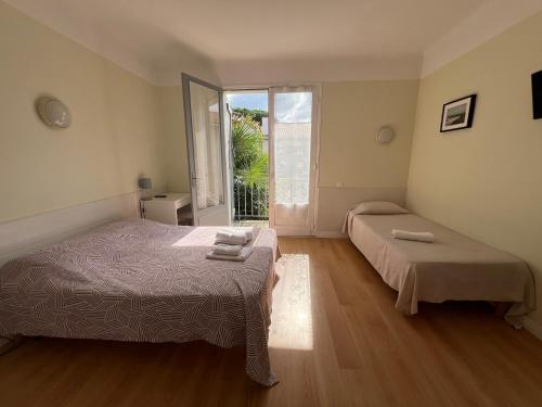 a bedroom with two beds and a window at Hôtel La Pergola - centre ville in Capbreton