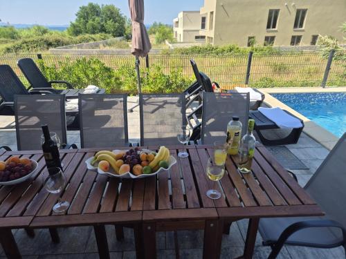 a wooden table with a bowl of fruit and wine bottles at Villa Tisa in Privlaka