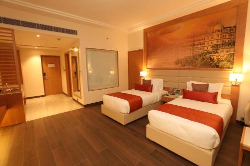 a hotel room with two beds and a couch at Regenta Central Udaipur, Court Circle in Udaipur