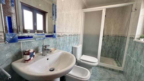 Un baño con lavabo, inodoro y ducha. en Chloe's Beach House, en A dos Cunhados