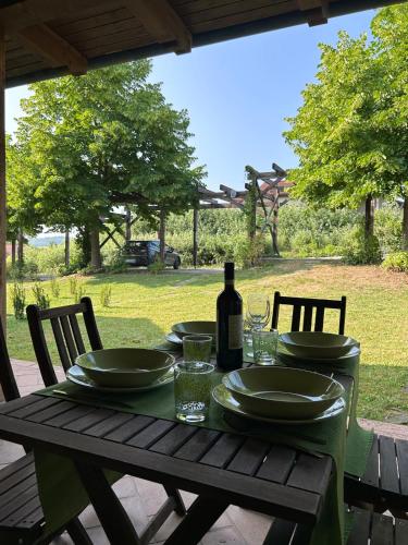 a wooden table with plates and a bottle of wine at Lagotto House-Apartment in the Langhe in Novello