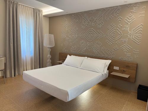 a bedroom with a large white bed and a wall at MIRARI Design Rooms in Cala Gonone