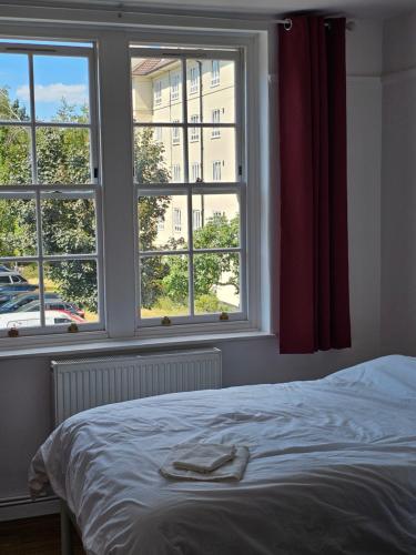 a bedroom with a bed and two windows at Flat in Hammersmith - Close to tube station in London