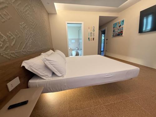 a large white bed in a room with a wall at MIRARI Design Rooms in Cala Gonone