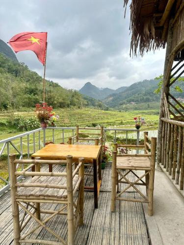 Una mesa y dos sillas en una terraza con una bandera. en Homestay khánh phù luông, en Làng Chiên (1)