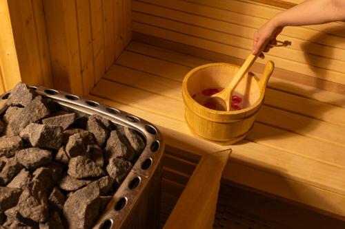 a person holding a wooden spoon in a bucket in a sauna at Idou Malabata Beach and SPA in Tangier