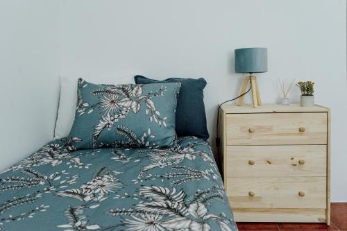 a bed with a blue comforter and a night stand at Quinta Alto da Capela in Setúbal