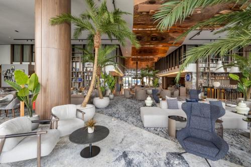 a lobby with palm trees and chairs and tables at Idou Malabata Beach and SPA in Tangier