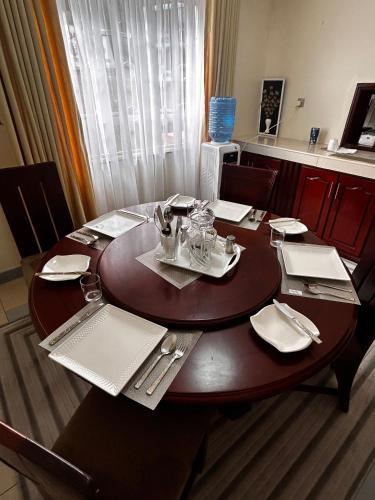 a wooden table with plates and utensils on it at Axis Guest House in Syokimau
