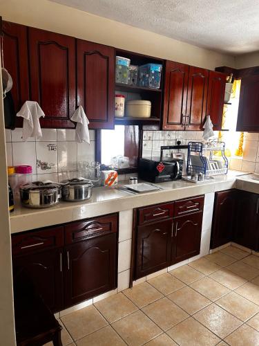 a kitchen with wooden cabinets and a counter top at Axis Guest House in Syokimau