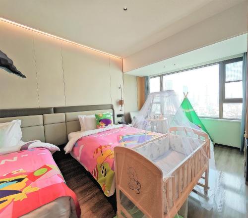 a bedroom with two twin beds and a crib at Shanghai Elong Hotel by the bund and Nanjing road Pedestrian street in Shanghai