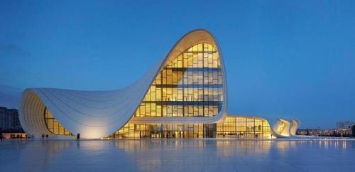 a large building with a large glass facade at night at Pilot By Haz Hotel in Baku