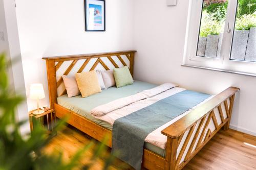 a bedroom with a wooden bed with pillows and a window at Stilvoll - Heimkino, Kochinsel, Parkplatz, Neubau & Mehr in Scheyern