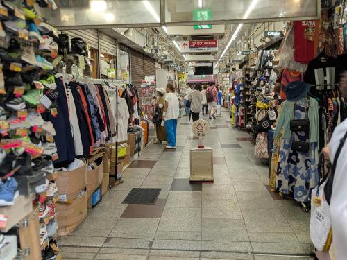 a group of people walking through a store aisle at 東京の中心地 Okachimachi Staypia in Tokyo