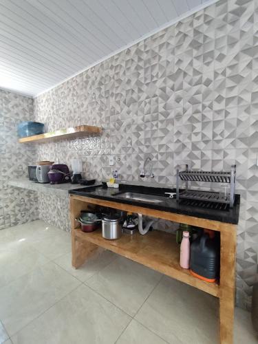 a kitchen with a sink and a wall with tiles at Charmoso Village no Povoado de Coqueiros in Jandaíra