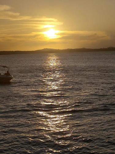 a boat on the water with the sun setting at Charmoso Village no Povoado de Coqueiros in Jandaíra