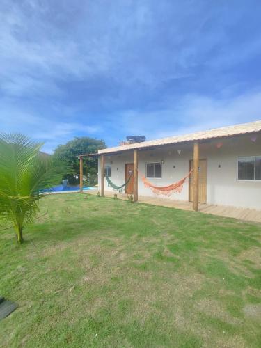 a house with a hammock in the yard at Charmoso Village no Povoado de Coqueiros in Jandaíra