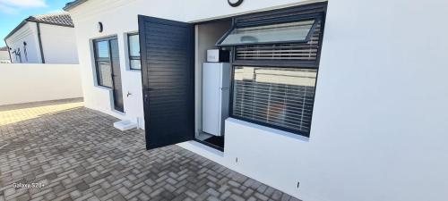 a white house with a window with a black shutter at 154 On Beach - Sandy Point Beach Estate in West Point