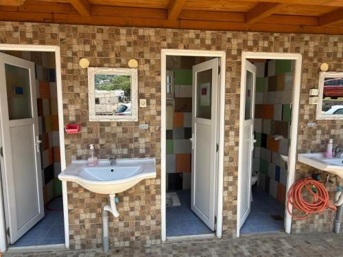 un baño con lavabo y dos espejos en Wooden Lakefront Bungalow, en Jablanica