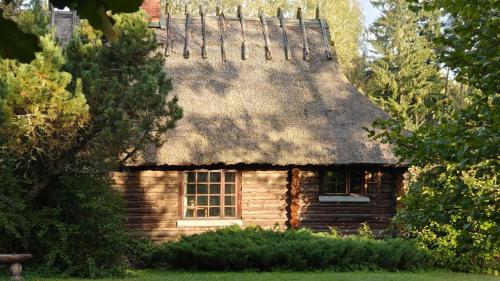 an old log cabin with a thatched roof at Käbliku Puhkemajad in Kanepi