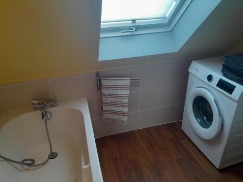 a bathroom with a tub and a washing machine at Appartement 4 couchages Le nid de l'écureuil in Donges