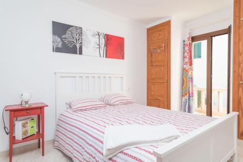 a white bedroom with a bed and a table at Can Joan in Cala Figuera