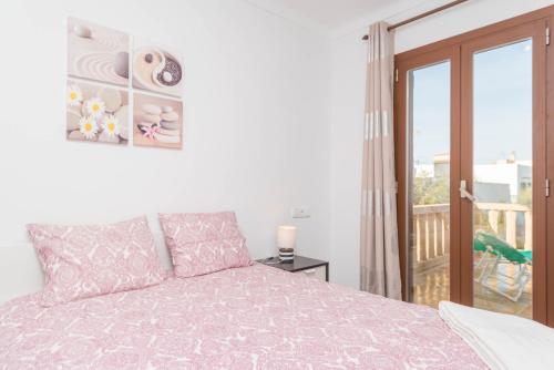 a bedroom with a pink bed and a balcony at Can Joan in Cala Figuera