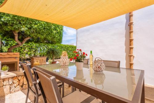 a table and chairs on a patio with a yellow umbrella at Can Joan in Cala Figuera