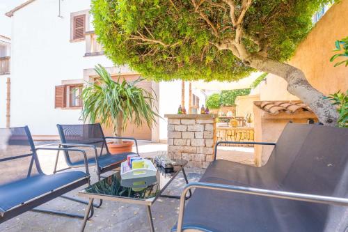 a group of chairs sitting next to a tree at Can Joan in Cala Figuera