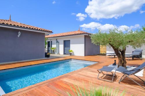 une piscine avec une terrasse en bois et une maison dans l'établissement Villa l'Escapade Landaise, à Parentis-en-Born