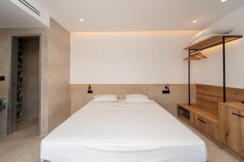 a bedroom with a white bed and a wooden cabinet at Paloma Seaesta Cabanas in Rhodes Town