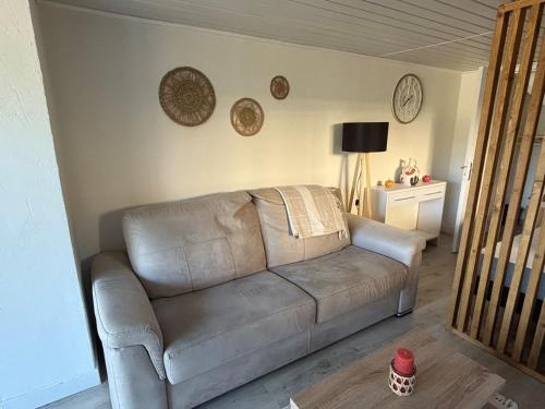a leather couch in a living room with plates on the wall at Studio équipé calme & confort in Bergerac