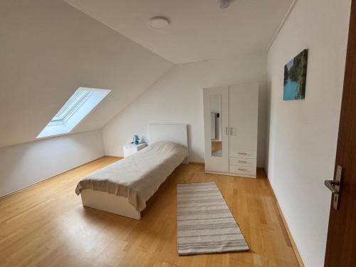 a white bedroom with a bed and a window at Ferienwohnung Immenzaun in Isernhagen