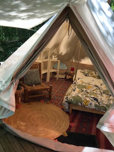Cette chambre comprend une tente avec un lit et une chaise. dans l'établissement Tente aménagée pour 1 ou 2 personnes, à Rennes-les-Bains