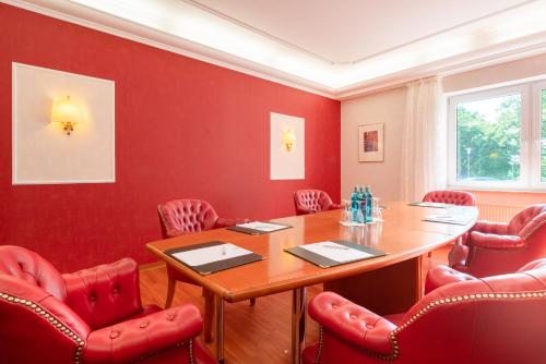a conference room with a wooden table and red chairs at Best Western Hotel Am Papenberg in Göttingen
