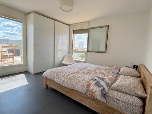 een slaapkamer met een bed en een groot raam bij Le Penthouse Ampère in Nanterre