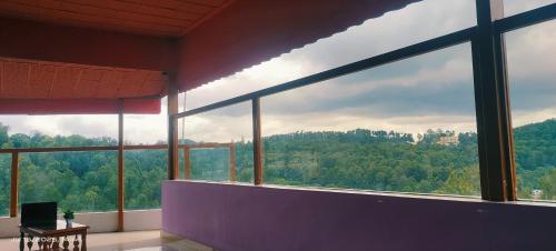 a room with a large window with a view of trees at Sky View Resort in Yercaud
