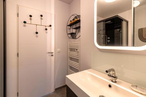 a white bathroom with a sink and a mirror at Splendide appartement T3 piscine et vue mer in Grosseto-Prugna