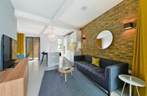 a living room with a black couch and a brick wall at Luxury Loft Apartment in London Bridge in London