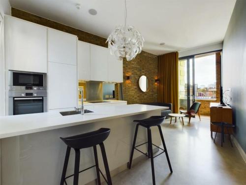 a kitchen with white cabinets and black bar stools at Luxury Loft Apartment in London Bridge in London
