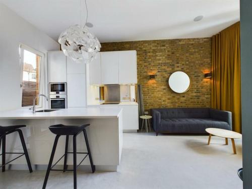 a kitchen and living room with white cabinets and a blue couch at Luxury Loft Apartment in London Bridge in London