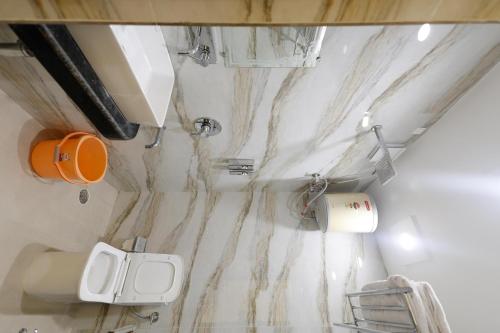 a bathroom with a marble wall with a toilet at Kudos Lush Homestay in Varanasi