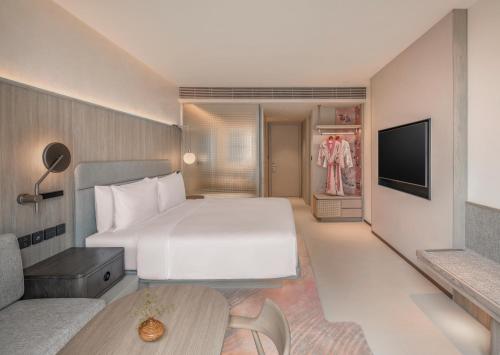 a bedroom with a large white bed and a tv at Kromo Bangkok, Curio Collection By Hilton in Bangkok